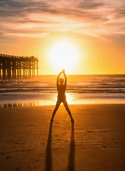 日落时在海滩上做瑜伽的女人 — 图库照片