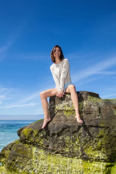 Γυναίκα κάθεται σε έναν βράχο από τον ωκεανό — Φωτογραφία Αρχείου