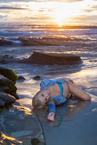 Schöne Frau an der Küste bei Sonnenuntergang — Stockfoto