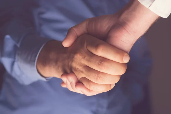 Handshaking of two business people. Partnership - Teamwork. Greeting, Form Of Communication. Light in scene come from down.