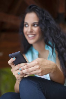 Sosyal ağ - yarış genç kadın kullanım akıllı telefon gülümseyen karışık. Onun arkadaşlarınızla iletişiminizi olmak telefon kullanır. Telefon üzerinde odaklanmak