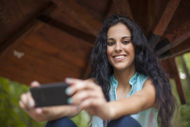 Sosyal ağ - yarış genç kadın kullanım akıllı telefon gülümseyen karışık. O arkadaşları temas olması için telefon kullanır