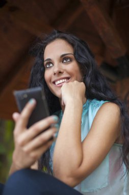 Sosyal ağ - karışık yarış genç gülümseyen kadın güzel gülümseme ile akıllı telefon kullanın. O arkadaşları temas olması için telefon kullanır