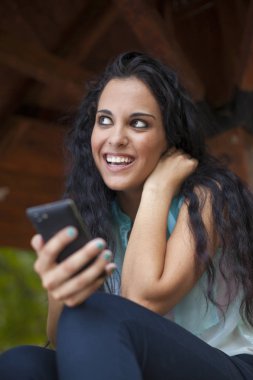 Sosyal ağ - yarış genç kadın kullanım akıllı telefon gülümseyen karışık. O arkadaşları temas olması için telefon kullanır