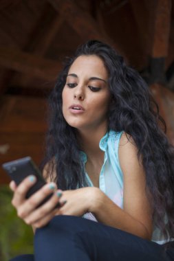 Sosyal ağ - yarış genç kadın kullanım akıllı telefon gülümseyen karışık. O arkadaşları temas olması için telefon kullanır