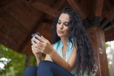 Sosyal ağ - yarış genç kadın kullanım akıllı telefon gülümseyen karışık. O arkadaşları temas olması için telefon kullanır