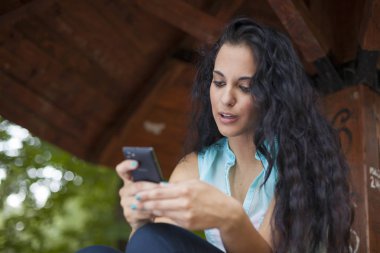 Sosyal ağ - yarış genç kadın kullanım akıllı telefon gülümseyen karışık. O arkadaşları temas olması için telefon kullanır