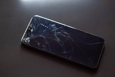 Siyah masaüstünde kırık dokunmatik ekranlı akıllı telefon