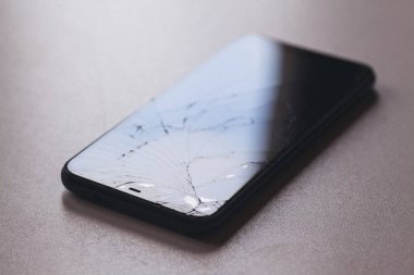 Siyah masaüstünde kırık ekranlı akıllı telefon