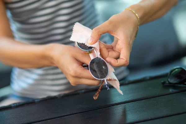 Woman hands wiping sun glasses with micro fiber wipe