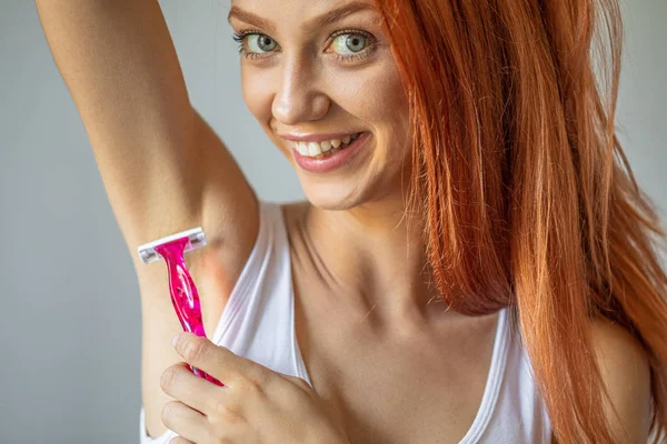 Усміхнена жінка голиться пахвою з рожевою бритвою — стокове фото