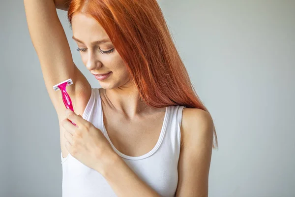 Mujer sonriente afeitándose la axila con afeitadora rosa —  Fotos de Stock