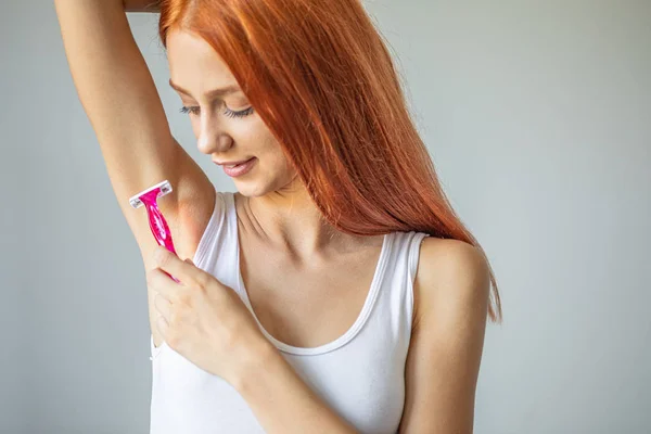 Mujer sonriente afeitándose la axila con afeitadora rosa —  Fotos de Stock