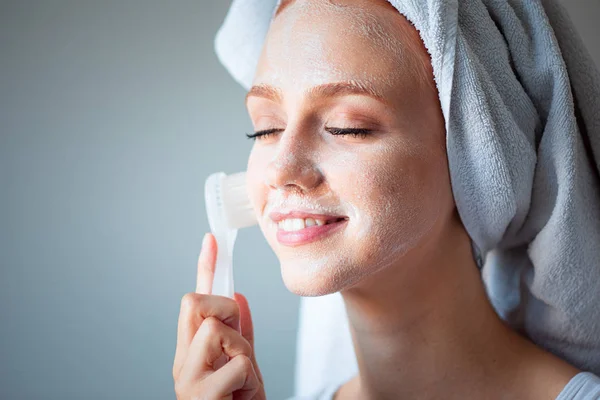 Woman washing cleaning face and skin with brush soap and wather