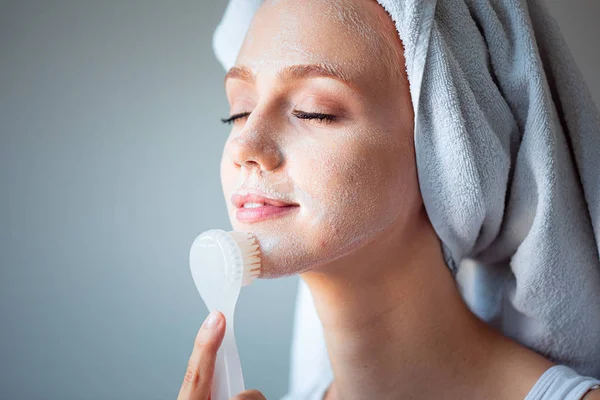 Woman washing cleaning face and skin with brush soap and wather