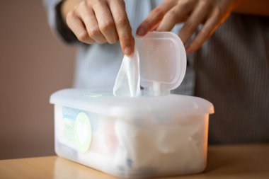 Islak mendiller evrenseldir. Kadın eli temizlik, ev ve ev için büyük plastik bir paketten bir mendil alır.