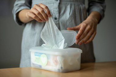 Islak mendiller evrenseldir. Kadın eli temizlik, ev ve ev için büyük plastik bir paketten bir mendil alır.