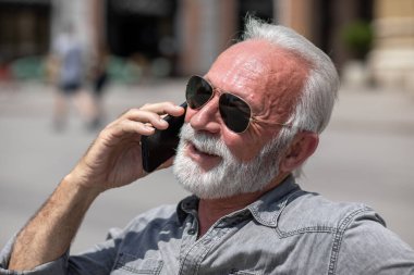 Yaşlı adam akıllı telefonlarda internet uygulaması kullanıyor, şehir içi stok fotoğrafı.