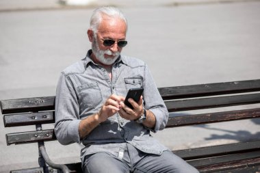 Yaşlı adam akıllı telefonlarda internet uygulaması kullanıyor, şehir içi stok fotoğrafı.