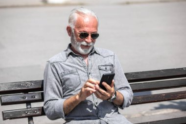 Yaşlı adam akıllı telefonlarda internet uygulaması kullanıyor, şehir içi stok fotoğrafı.