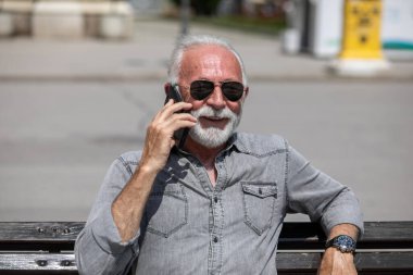 Yaşlı adam akıllı telefonlarda internet uygulaması kullanıyor, şehir içi stok fotoğrafı.