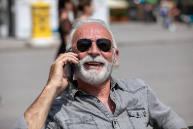 Yaşlı adam akıllı telefonlarda internet uygulaması kullanıyor, şehir içi stok fotoğrafı.