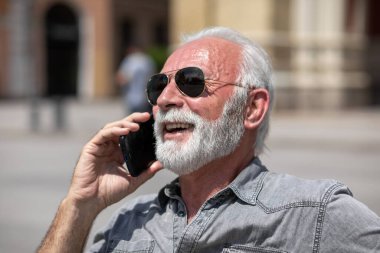 Yaşlı adam akıllı telefonlarda internet uygulaması kullanıyor, şehir içi stok fotoğrafı.