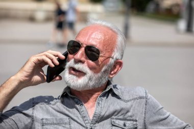 Yaşlı adam akıllı telefonlarda internet uygulaması kullanıyor, şehir içi stok fotoğrafı.