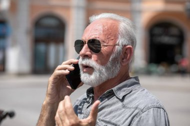 Yaşlı adam akıllı telefonlarda internet uygulaması kullanıyor, şehir içi stok fotoğrafı.