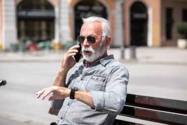 Yaşlı adam akıllı telefondan konuşuyor, şehirli arkaplan fotoğrafı.