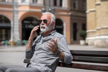 Yaşlı adam akıllı telefon kullanıyor, şehrin arka plan fotoğrafı.