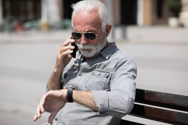 Starý Muž Dívá Hodinky Mluvit Smartphone Městské Město Pozadí Stock — Stock fotografie