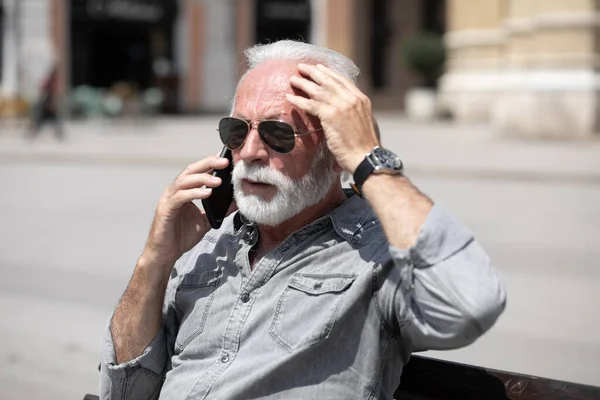 Old man forget and remember something, speak on smartphone, urban city background stock photo