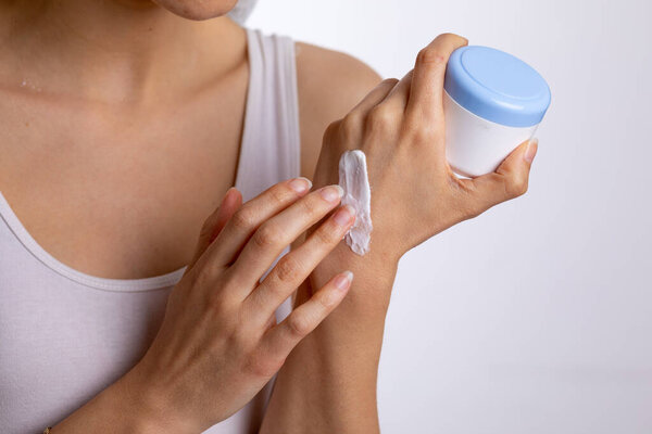 Young woman applying hand cream to protect and care skin, close up.