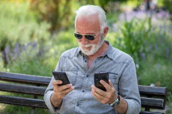 Old man compare two smartphones