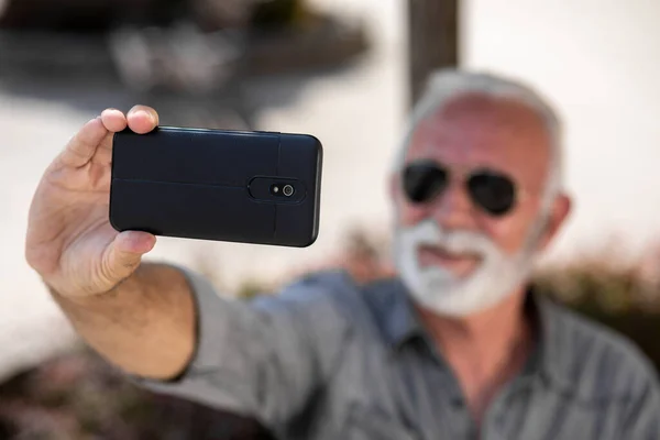 An older tourist man enjoys a vacation and takes a selfie on the street