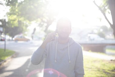 Parkta akıllı telefondan konuşan bir adam, açık havada ateş eden, lens flaşlı arka lambalı.