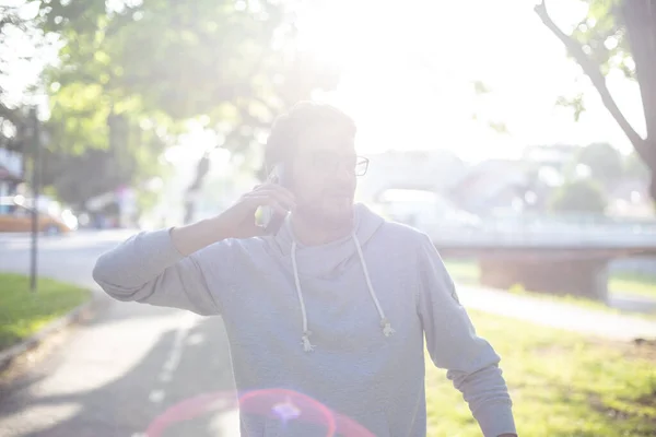 在公园里用智能手机说话的男人 户外射击 镜头反光 — 图库照片