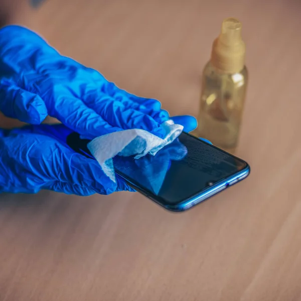 Γυναικείο Χέρι Μπλε Γάντια Καθαρίζοντας Κινητό Τηλέφωνο Smartphone Ξύλινη Επιφάνεια — Φωτογραφία Αρχείου