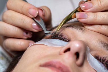 Kirpiklerin iyileştirme prosedürü Cımbızla uzatılmış uzun kirpikli kadın gözleri