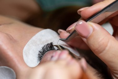 Kirpiklerin iyileştirme prosedürü Cımbızla uzatılmış uzun kirpikli kadın gözleri