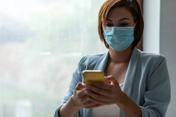 Donna Con Maschera Facciale Utilizzando Smartphone Indoor — Foto Stock