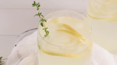 Soğuk limonata veya alkollü kokteyl limon, biberiye ve hafif bir arka plan üzerinde cam bardaklarda buz ile.