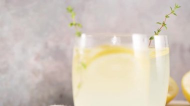 Soğuk limonata veya alkollü kokteyl limon, biberiye ve hafif bir arka plan üzerinde cam bardaklarda buz ile.