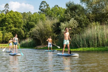Kadın ve erkek paddleboarding göl kenarında ayağa kalk. Genç çiftler gölde su sporları yapıyoruz. Yaz tatili sırasında erkek ve kadın turist.