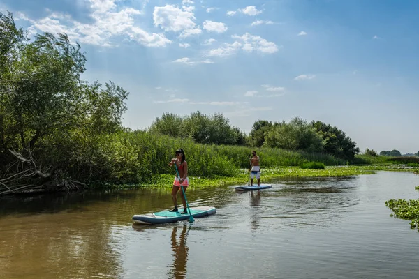 男人和女人站在湖上 Paddleboarding 年轻夫妇正在湖边做水上运动 女游客在暑假期间的旅行 — 图库照片