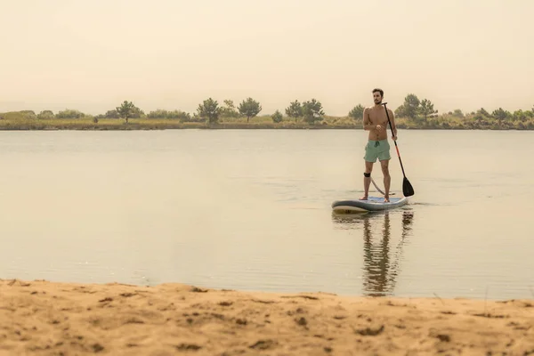 Adam Paddleboarding Göl Kenarında Ayakta Göl Kenarında Sporları Yapan Genç — Stok fotoğraf