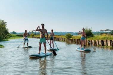 Adam ve kadın paddleboarding göl kenarında ayağa kalk. Göl kenarında su sporları. Yaz tatili sırasında erkek ve kadın turist.