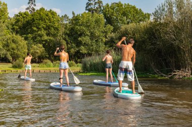 Adam ve kadın paddleboarding göl kenarında ayağa kalk. Göl kenarında su sporları. Yaz tatili sırasında erkek ve kadın turist.