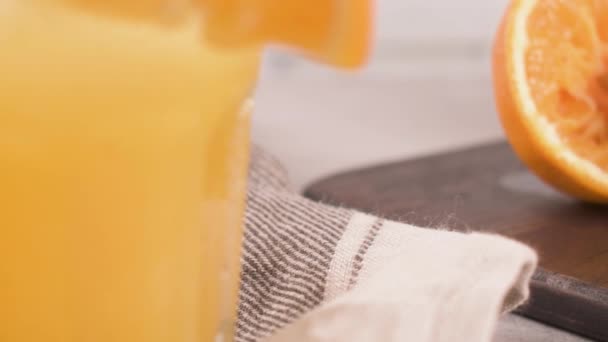 新鮮な有機オレンジ ジュース ガラスのテーブルの上に自家製オレンジ果汁 — ストック動画